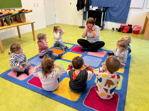 Kinder sitzen im Kreis im Musikunterricht